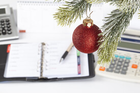 Personal calendar on desk behind Christmas ornament