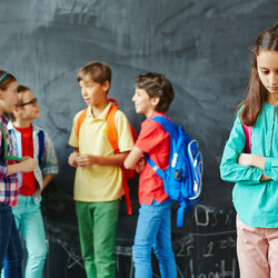 Lonely schoolgirl on background of her classmates having talk