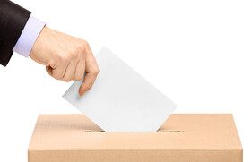 Man's hand inserting ballot into ballot box