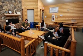 Students visiting around a table inside a log building